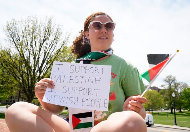 Kenzie Rounds, an Ohio State University senior from Maryland, sat outside the Ohio Union on Friday afternoon waving a Palestinian flag and holding a sign saying, "I support Palestine. I support Jewish people."  She said she was present at the protest Thursday night, but left before arrests began.