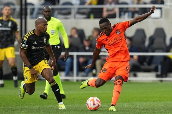 Mar 12, 2024; Columbus, OH, USA; Houston Dynamo forward Ibrahim Aliyu (18) shoots past Columbus Crew midfielder Darlington Nagbe (6) during the second half of the Concacaf Champions Cup soccer game at Lower.com Field. Mandatory Credit: Adam Cairns-USA TODAY Sports