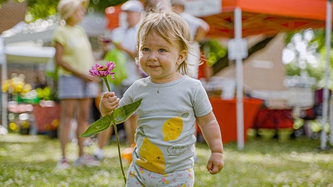 A young marketgoer shows off a freshly bought bloom at the Westgate Farmers Market, which is to hold a kickoff market May 18 before opening for the season June 1.